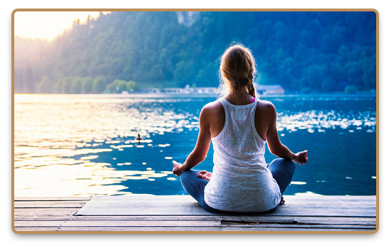 Nyugodt nő meditál a mólón a tónál