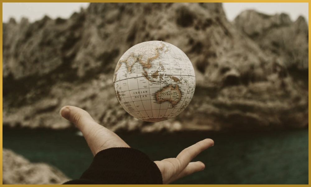 Man practices telekinesis by levitation of a globe with a lake and rocks in the background