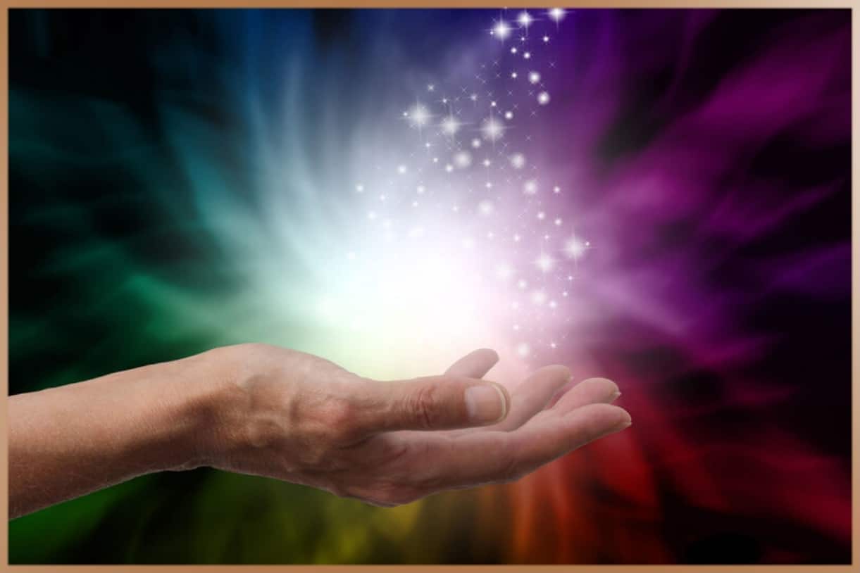 Bright white light as energy in the hand of a reiki healer with colorful background