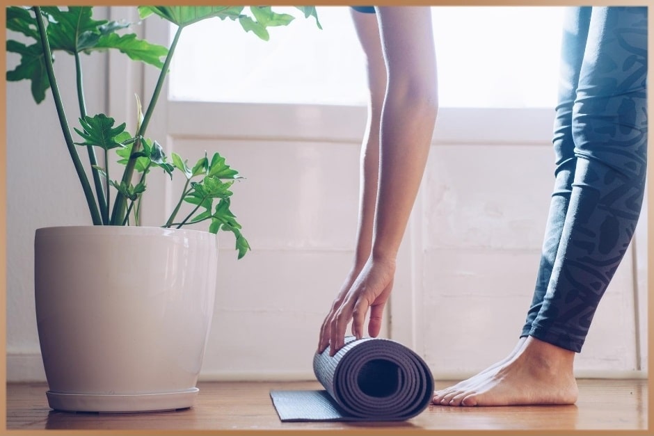 Woman folds her yoga mattress at home before starting yoga practice