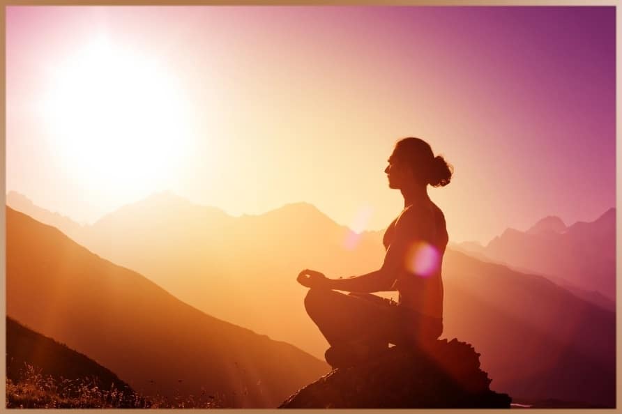 Woman meditates between the mountains in the sunset