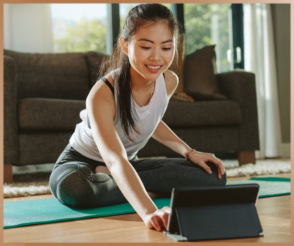 Woman practices yoga in at home from an online course on her tablet