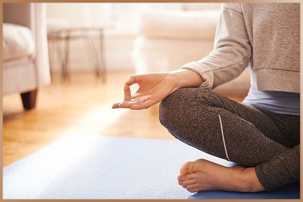 Woman practices meditation at home in yoga pants