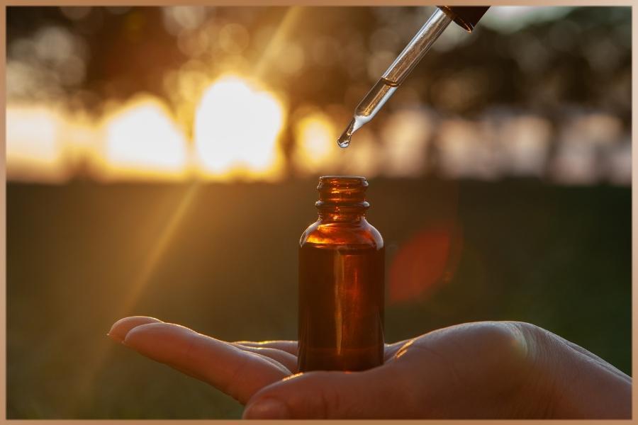 Spiritual healer is pouring flower essence drops into a glass vial in sunshine