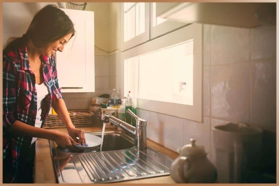 Happy woman washing dishes after practicing mindfulness meditation