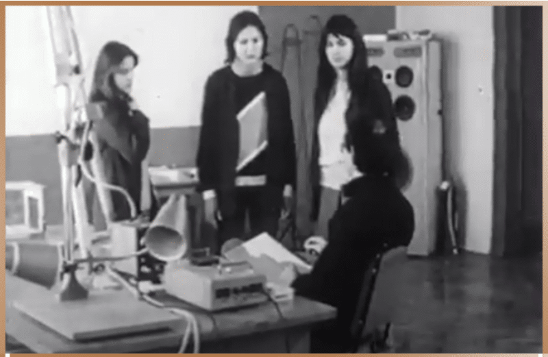 1990s archival photo of George Egely instructing high school students on using the Egely Wheel Vitality Meter amidst various scientific apparatus.