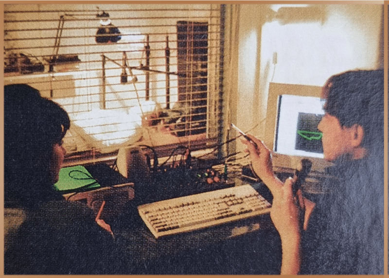 1990s researchers at a bioenergy lab with an Egely Wheel, surrounded by early computers and experimental equipment, embodying the era's quest to understand life's unseen energies.