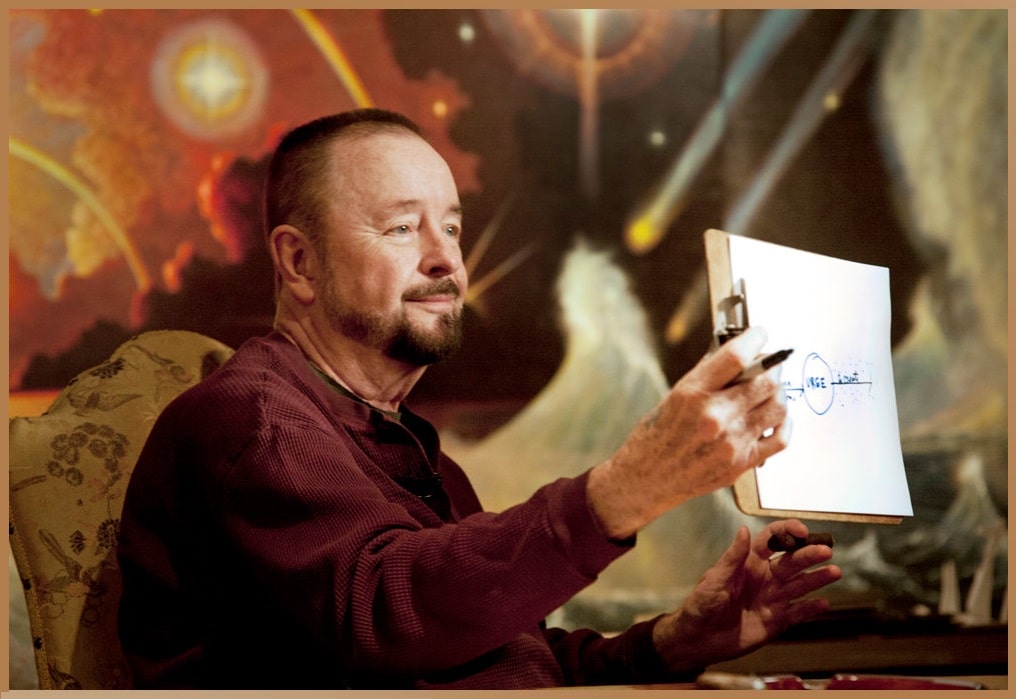 A man resembling Ingo Swann sits pensively with a clipboard in hand, reminiscent of remote viewing sessions, against a backdrop of cosmic-inspired artwork.