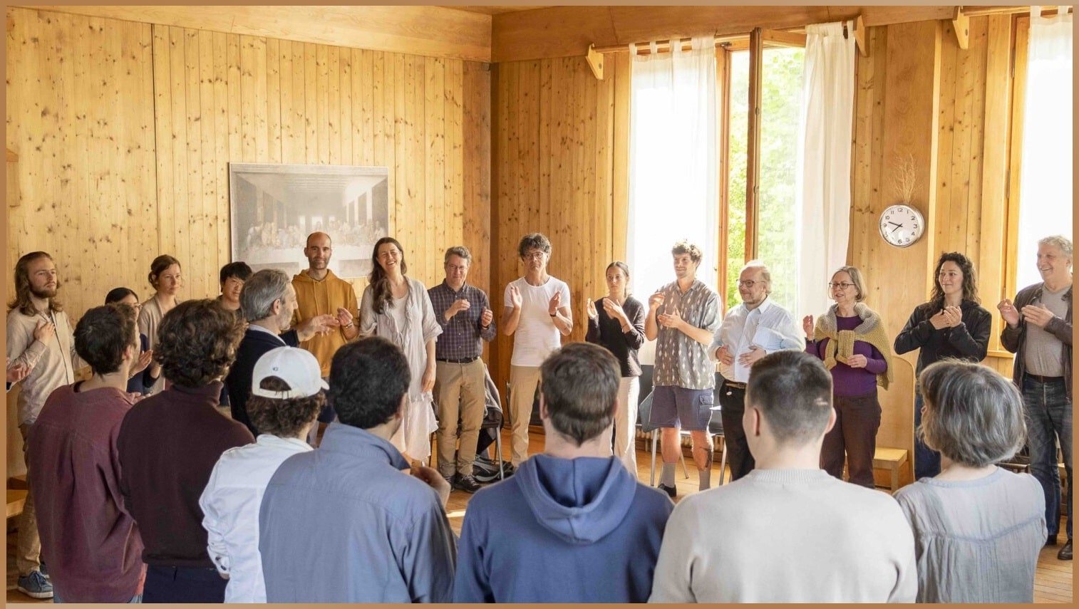 A diverse group of individuals participating in a workshop at the Goetheanum Campus, engaged in a collective, meditative activity to foster a deeper connection with the physical, emotional, and intellectual realms.