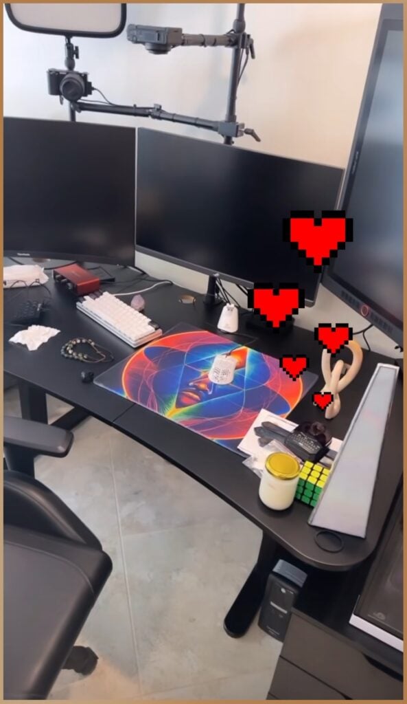 Zachariah Kalahiki's desk showing an Egely Wheel on a vibrant, colorful mat and a Rubik’s Cube among various personal and tech items, highlighting the blend of spirituality and intellectual challenge.